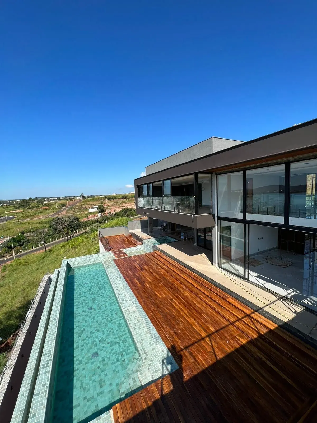 Deck de madeira e piscina de borda infinita da Casa M&G