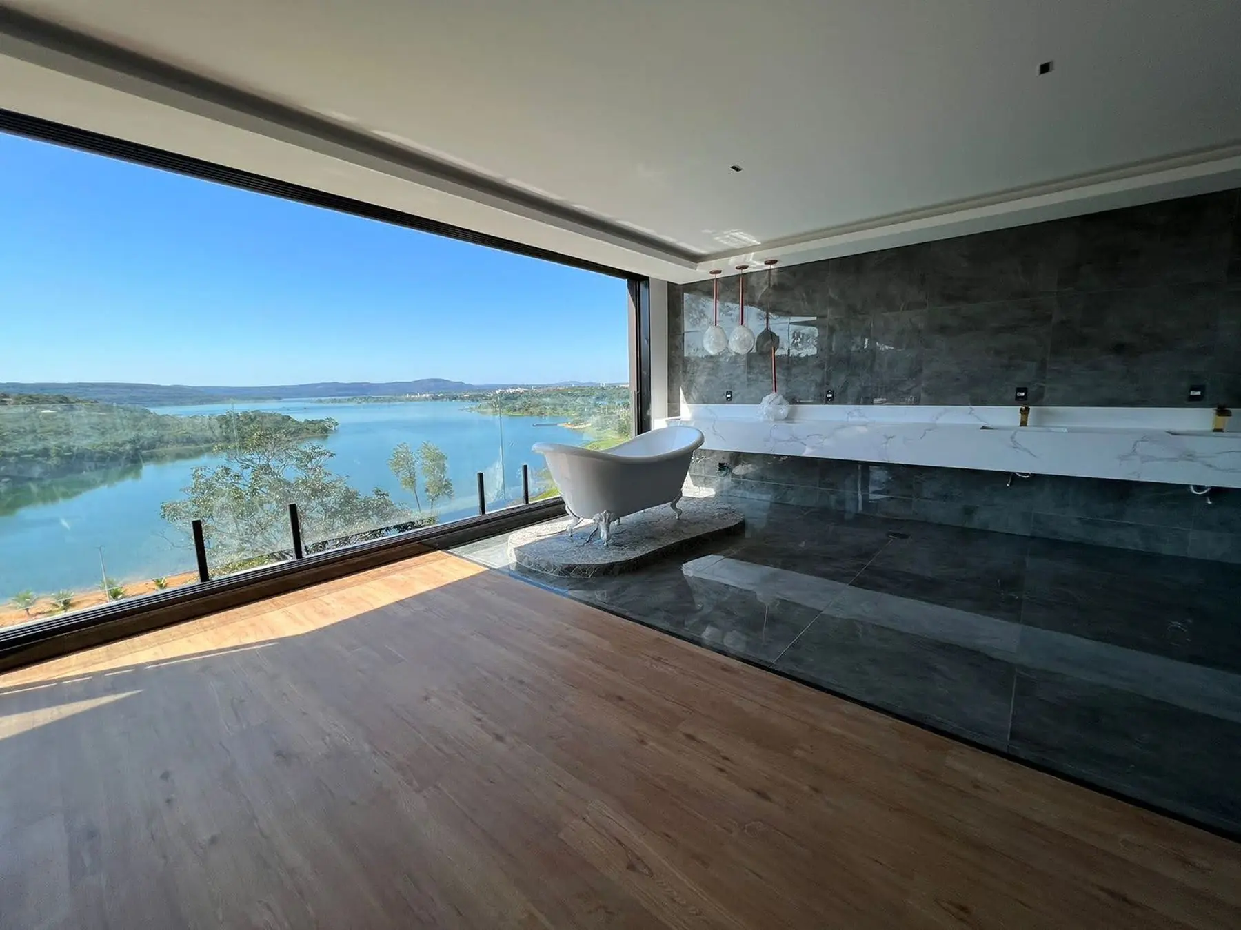 Suíte da Casa M&G com banheira e janela panorâmica para o lago